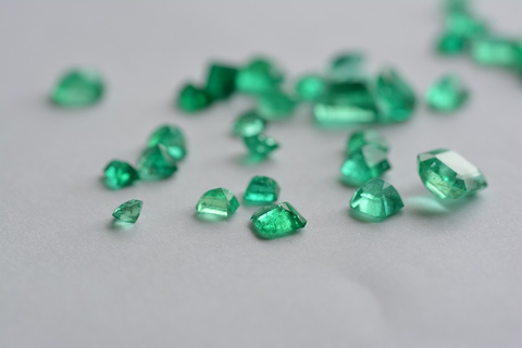 Emerald gems of various sizes spread out on a table.