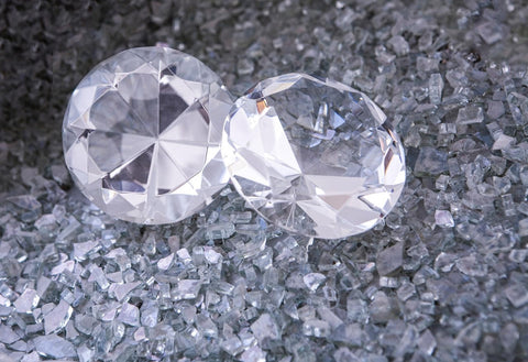 Two diamonds lying on top of shattered glass