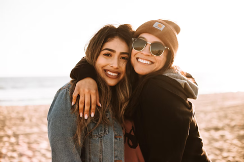 2 women smiling on a beach in warm clothes