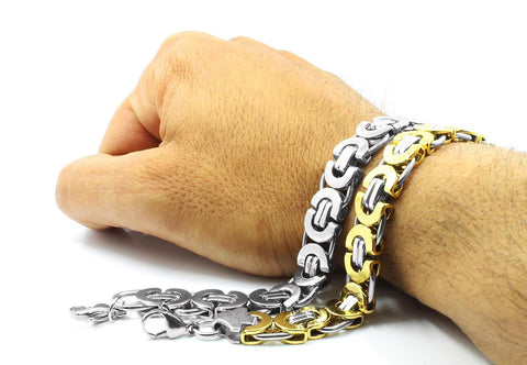  A man's wrist with two chain bracelets.