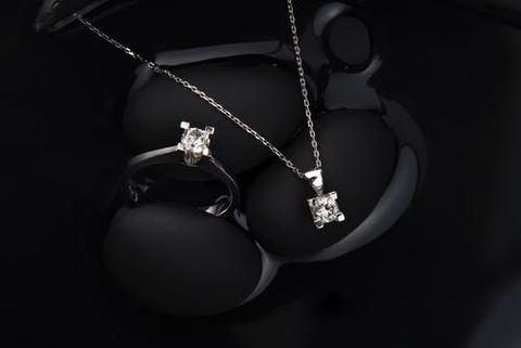 a diamond necklace and a diamond ring on a black velvet backdrop
