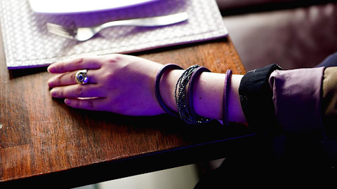 a woman's arm on a table with several dark bracelets