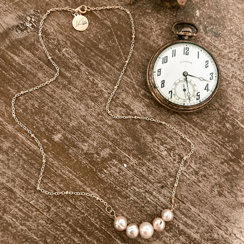 A necklace with five pearls on a table.