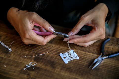 A woman trying to repair a necklace. 
