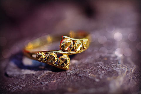 an ornate twisted gold ring on a purple table
