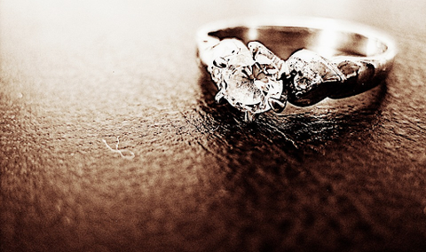 a silver round diamond ring on a brown table