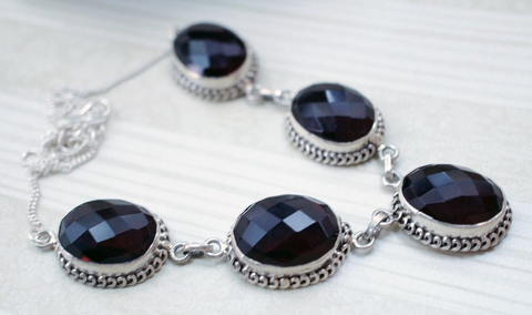  a multiple stone pendant fitted with dark garnets and a silver border on a white background