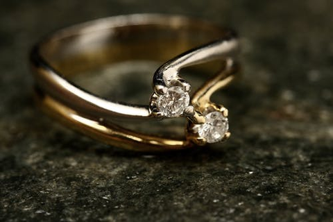  a twisted gold ring set with glittering white stones on a granite table