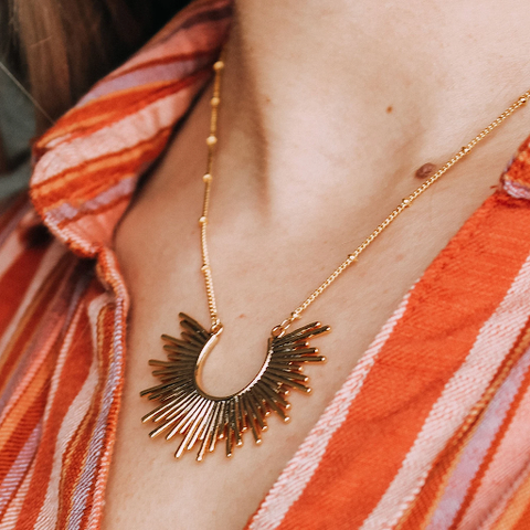 A woman wearing a gold Boho Babe Necklace designed and handcrafted by the artisans at LaCkore Couture.