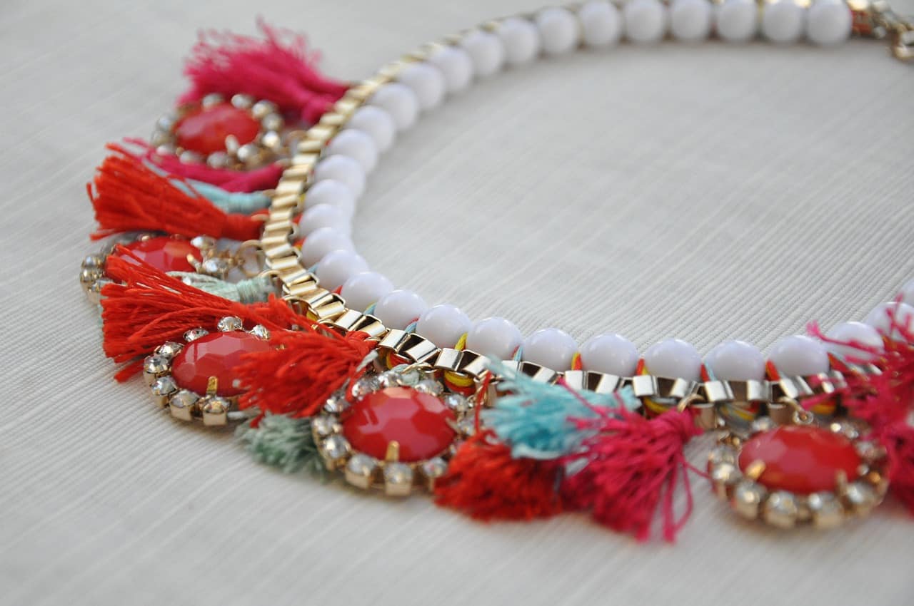 a colorful red, blue, and silver necklace on a white table