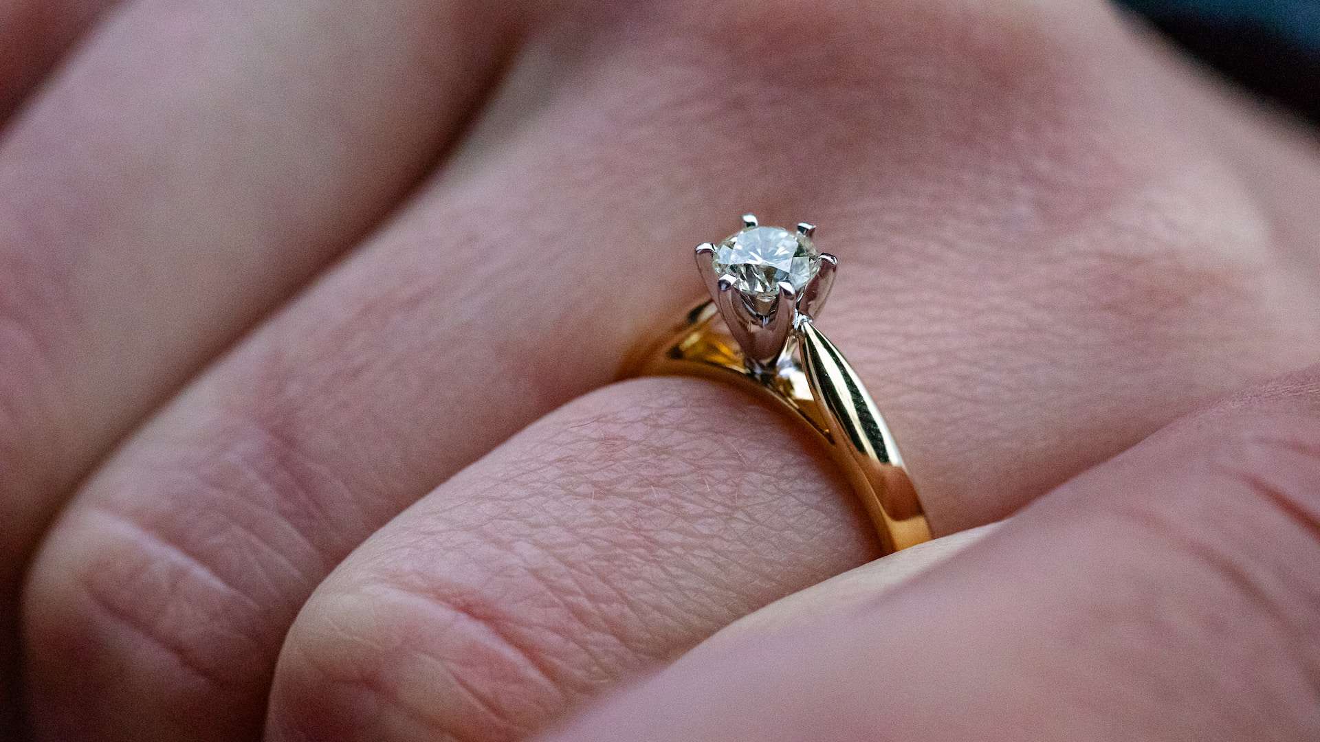 a gold diamond ring on a hand