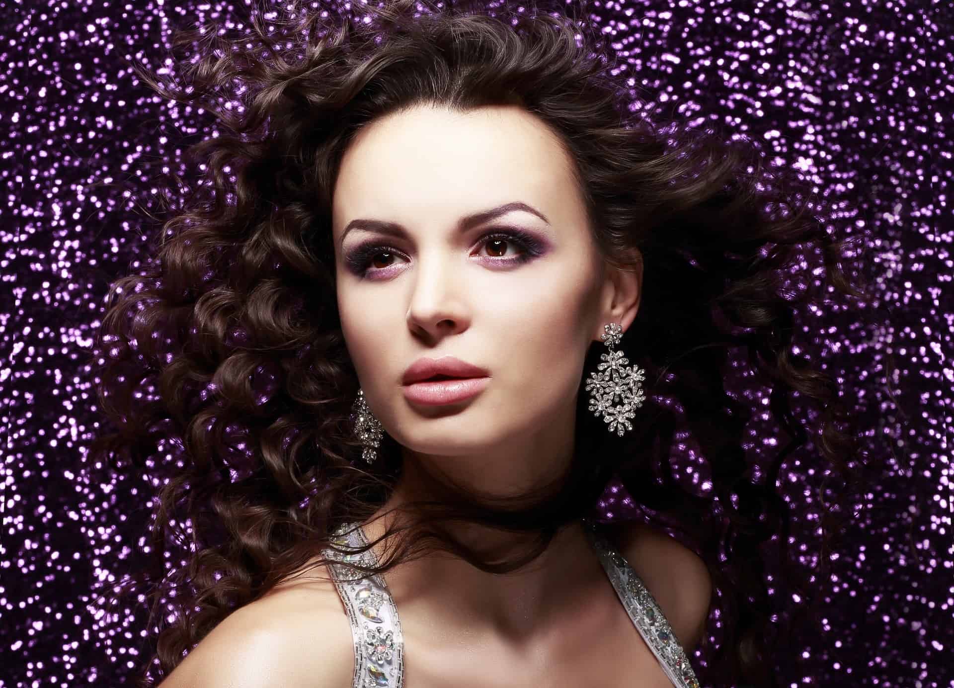 A Woman Modeling Earrings With Sparkly Background