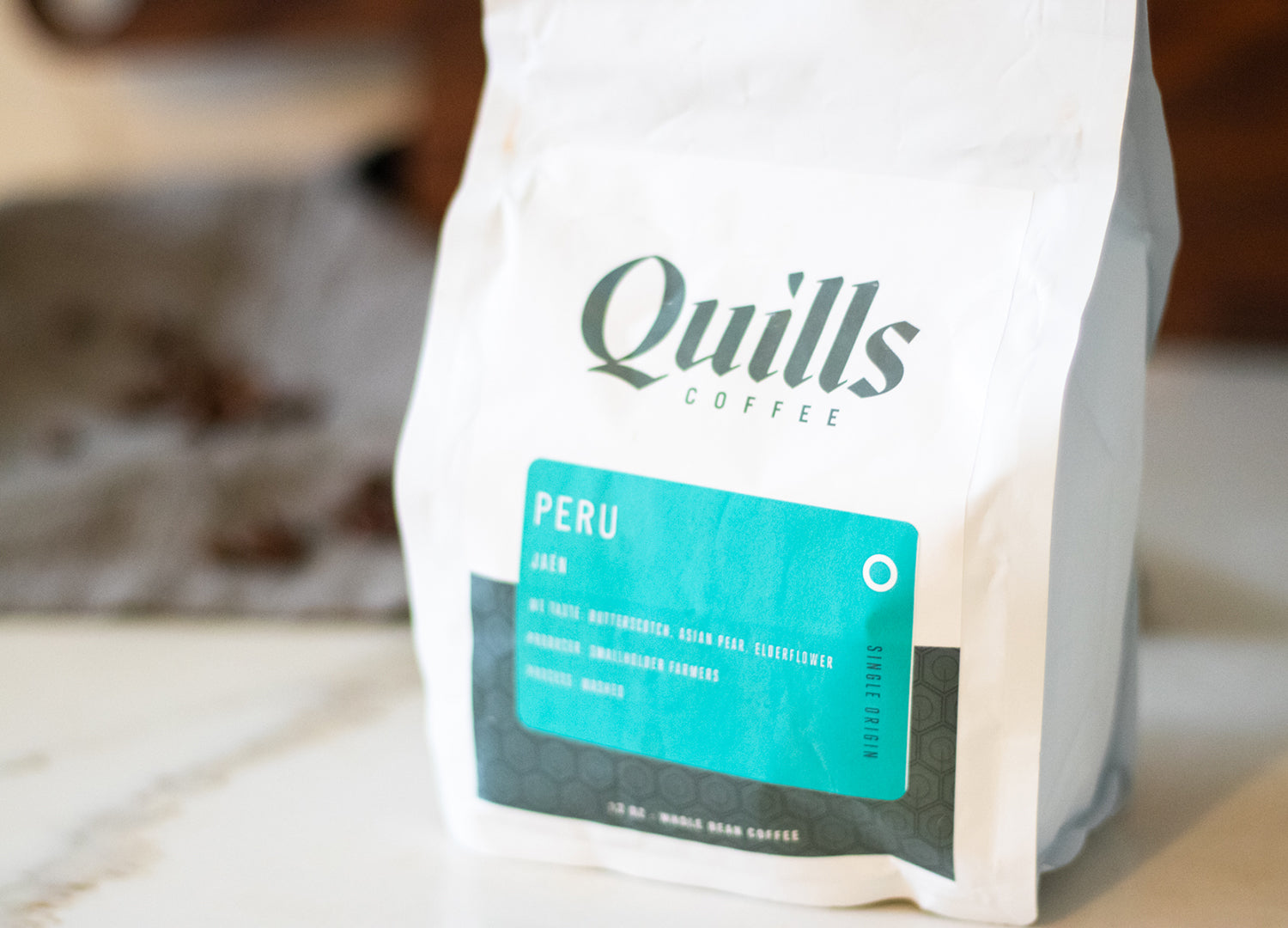 Quills Peru coffee bean bag resting on a counter ready to be ground