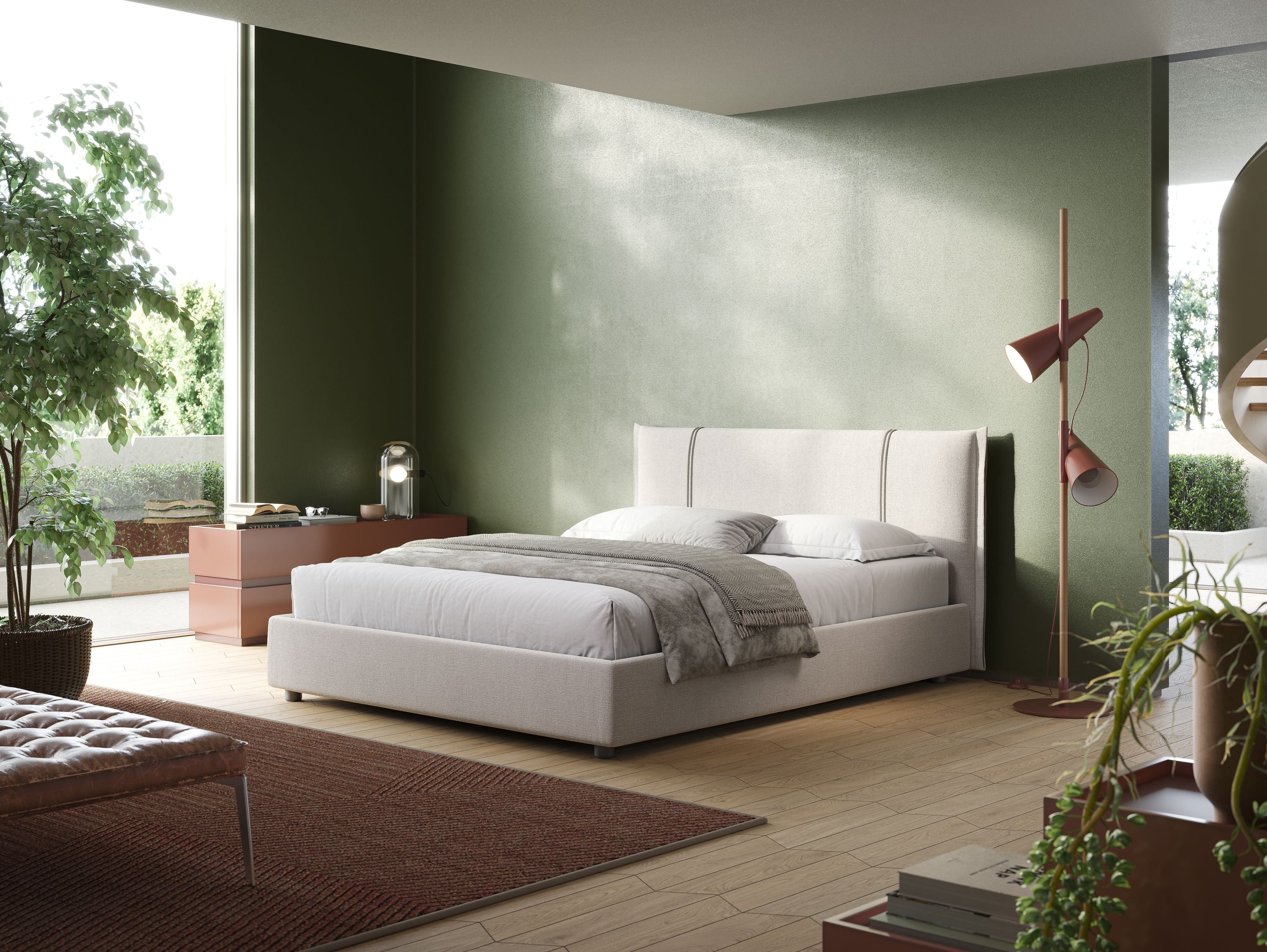 Una camera da letto moderna con un letto Alicia beige imbottito con vano contenitore in tessuto impermeabile T14 di Letti.store contro una parete verde. La biancheria da letto comprende lenzuola bianche e grigie. A sinistra, c'è una cassettiera marrone adornata con piante e una lampada a globo. Una lampada da terra rosa è posta accanto a un tappeto rosso sul pavimento. Ampie finestre inondano la stanza di luce naturale, offrendo viste sulla vegetazione lussureggiante all'esterno.