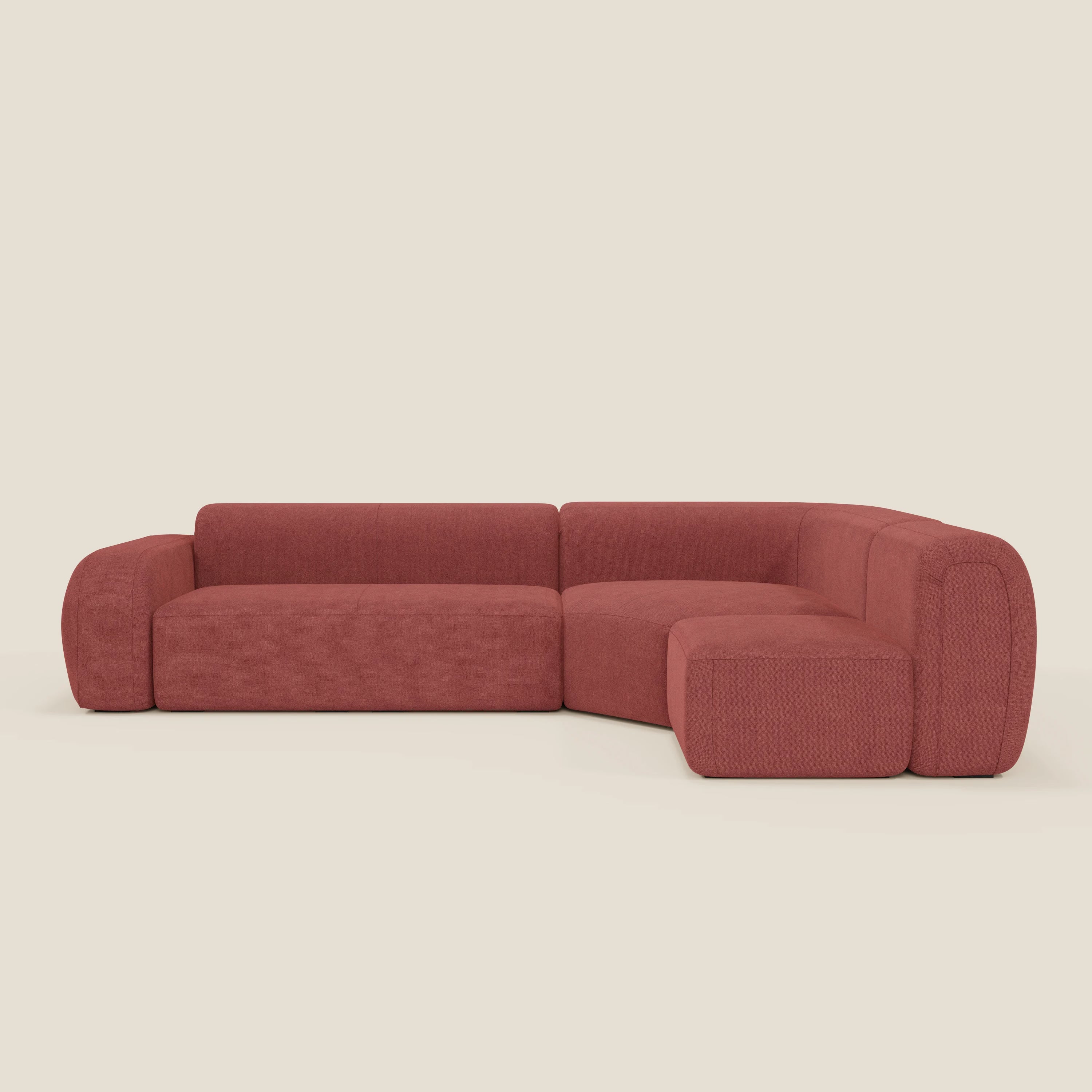 Il divano BonBon angolare componibile e modulare di Divani.Store è caratterizzato da spessi cuscini e ampi braccioli in tessuto smacchiabile T23 rosso ciliegia, che offrono un look accogliente e moderno con bordi arrotondati e design minimalista.