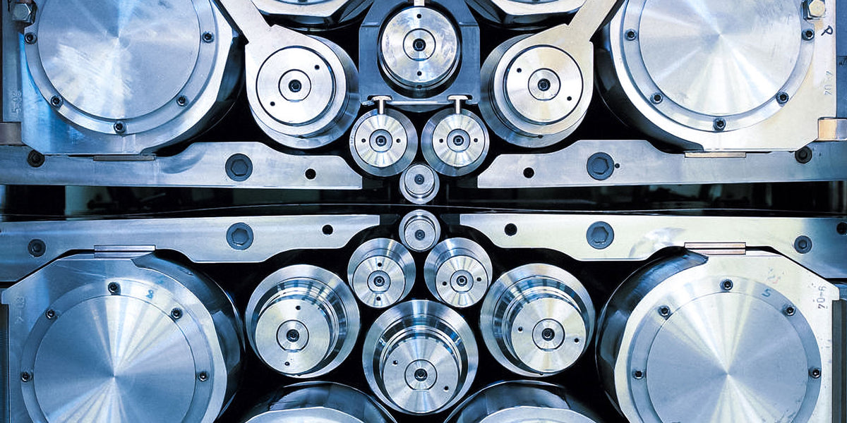 A steel press with smooth gears that roll the steel into place to be pressed flat.