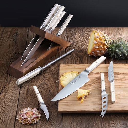 Lifestyle photo of the EVEREST Series 6 piece TAI knife block combo with white handles. Various knives are placed around the knife set.