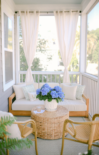 Contemporary front porch idea with blue hydrangeas and wicker seating