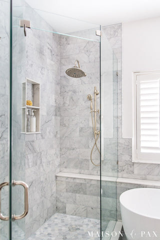 Chrome accents against marble stone shower for bathroom