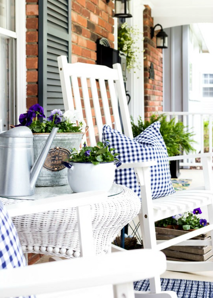 Modern farmhouse front porch with gingham pillows and potted plants