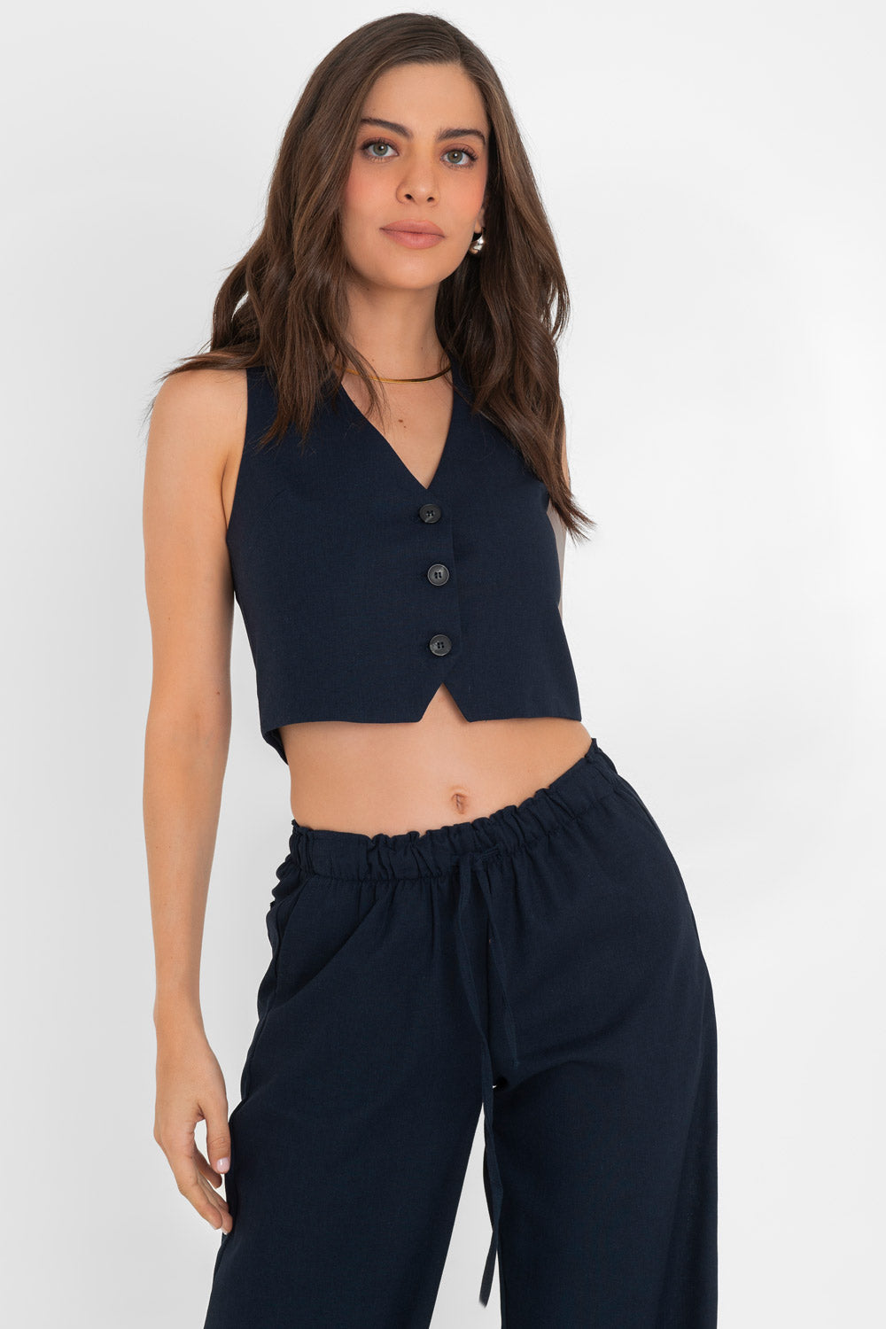 Woman in a navy blue sleeveless buttoned crop top and matching drawstring pants.