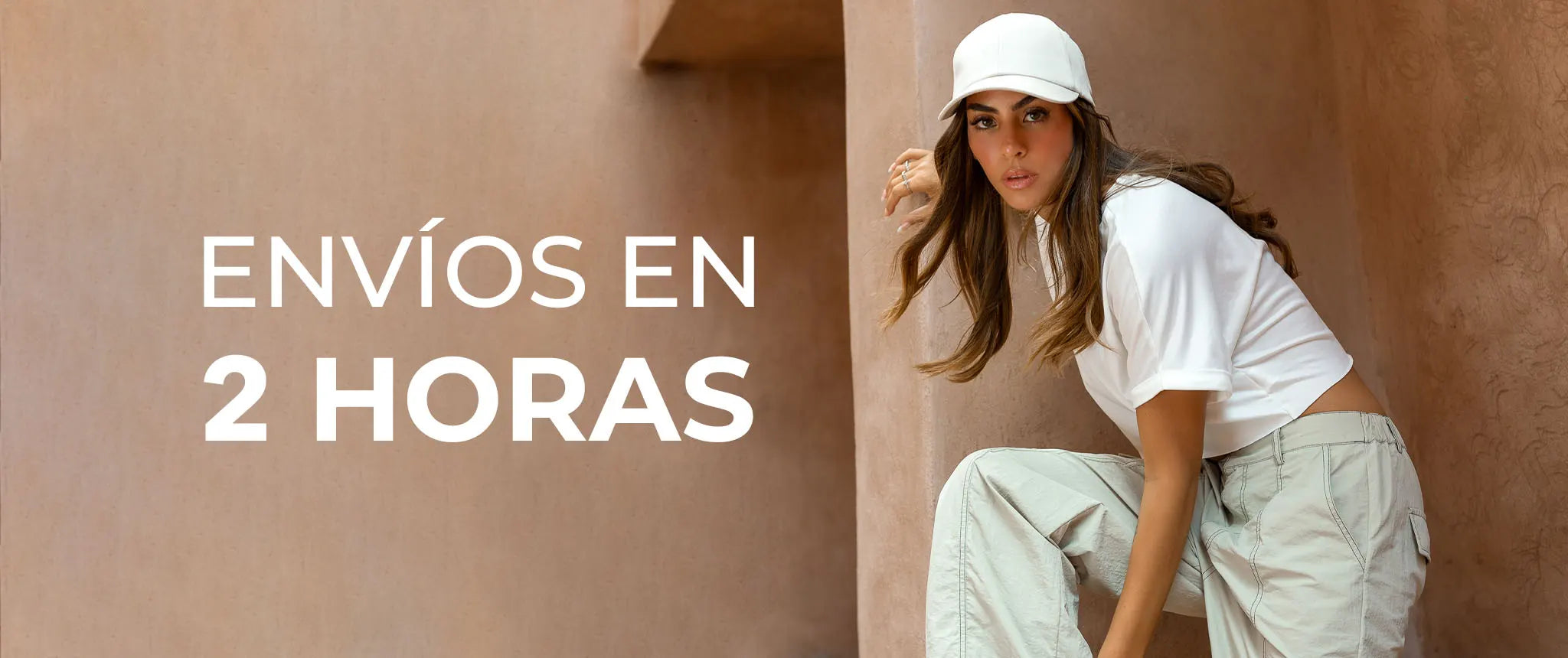 Mujer a la moda con gorra blanca y camiseta posando junto al texto 'ENVÍOS EN 2 HORAS'.