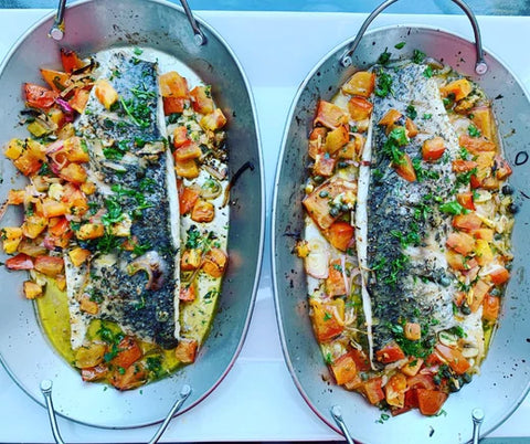 Two trays with fish roasted with herbs and vegetables 