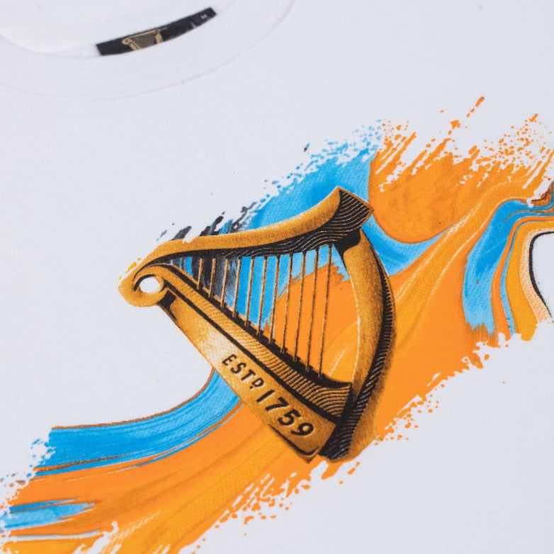 Close detail of the Guinness Storehouse Exclusive white sweatshirt with the iconic Guinness harp on an blue and orange texture.
