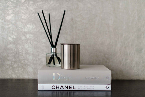 Eco-luxury candle and reed diffuser on coffee table books