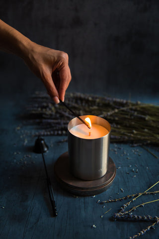 Hand lighting a stainless steel votive candle