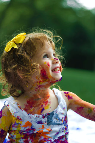 Smiling toddler with paint on face - Rainbow Yoga Training