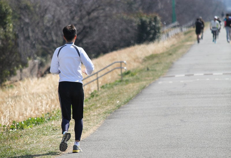 河川敷でランニングする男性の後ろ姿