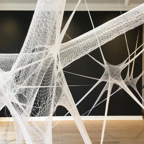 Fine white knitted lace textile sculpture immersive installation on an art gallery black wall background