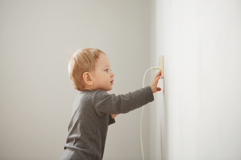 Niño curioso tocando enchufe seguridad hogar