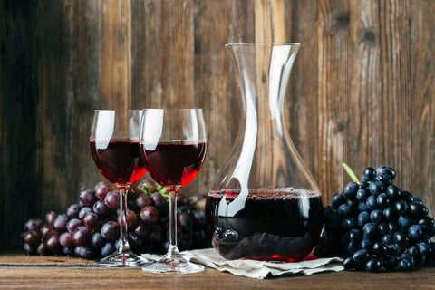 Decanting wine, red wine and two glasses, grapes, wooden background