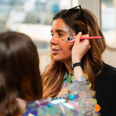 An eco glitter artist doing a glitter moon on a clients face