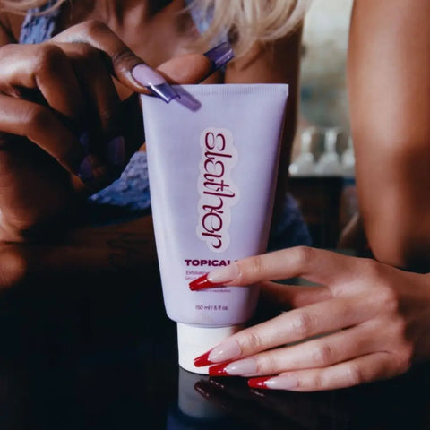 Serums for smooth skin are showcased as two individuals admire a Topicals exfoliating product with polished nails