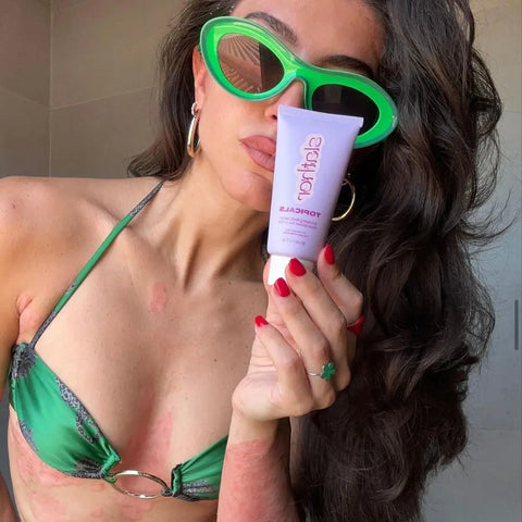 Serums for the face are held by a woman in green sunglasses and bikini, highlighting skin care for visible results