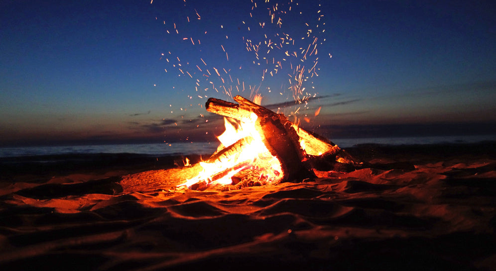 campfire at dusk with glowing embers and sparks rising