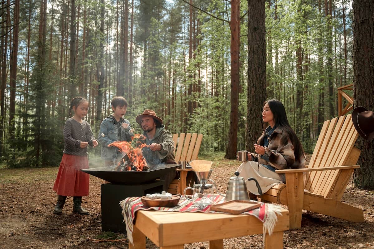 A family cooks dinner at a campsite over a fire