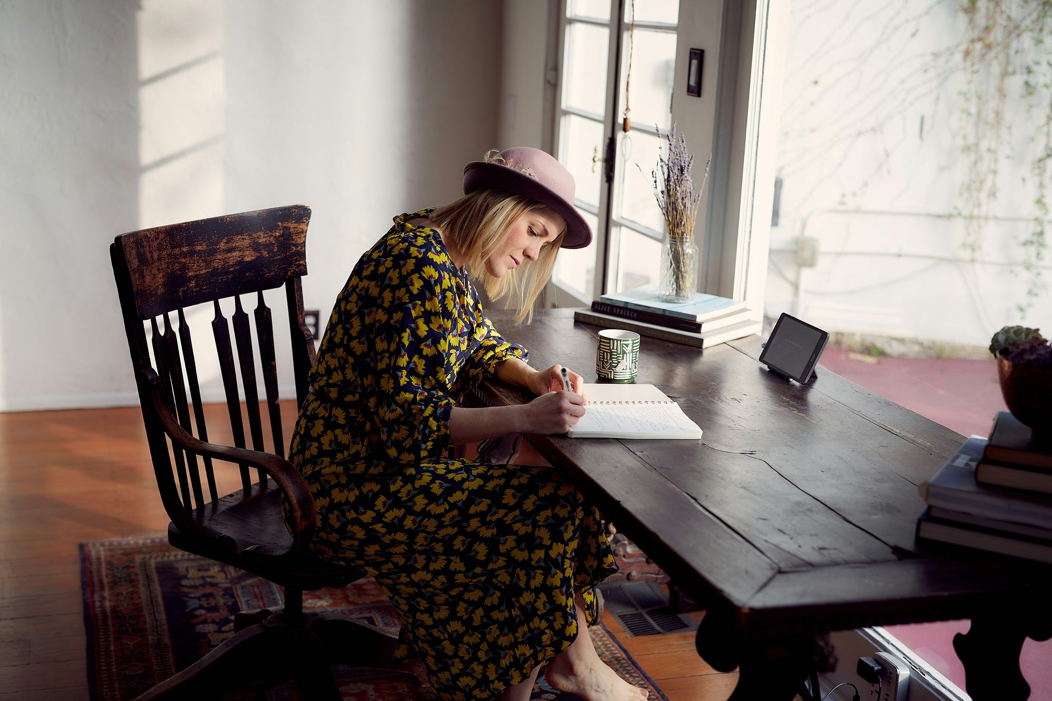 young woman sitting at a table and writing a shopping list