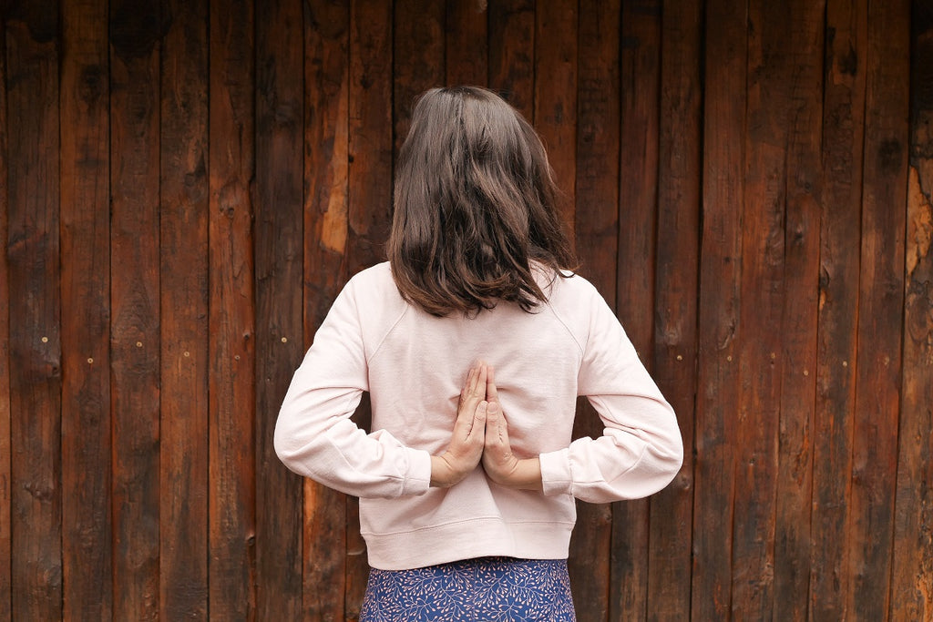 young woman with praying hands behind her back