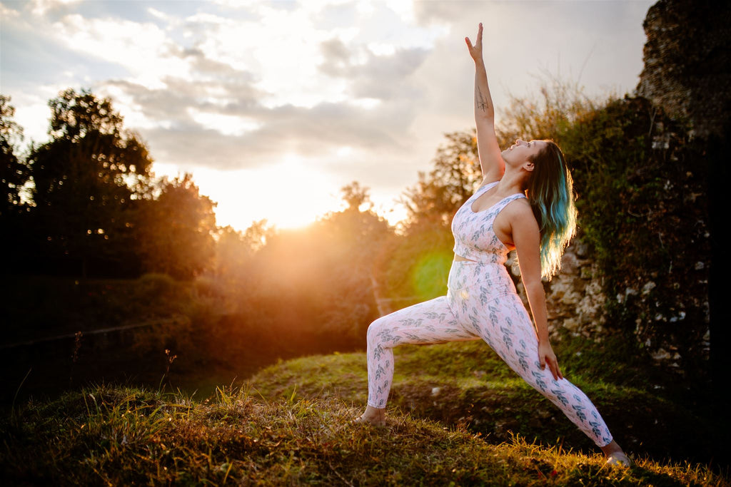 jeune femme dans la posture du guerrier au coucher du soleil