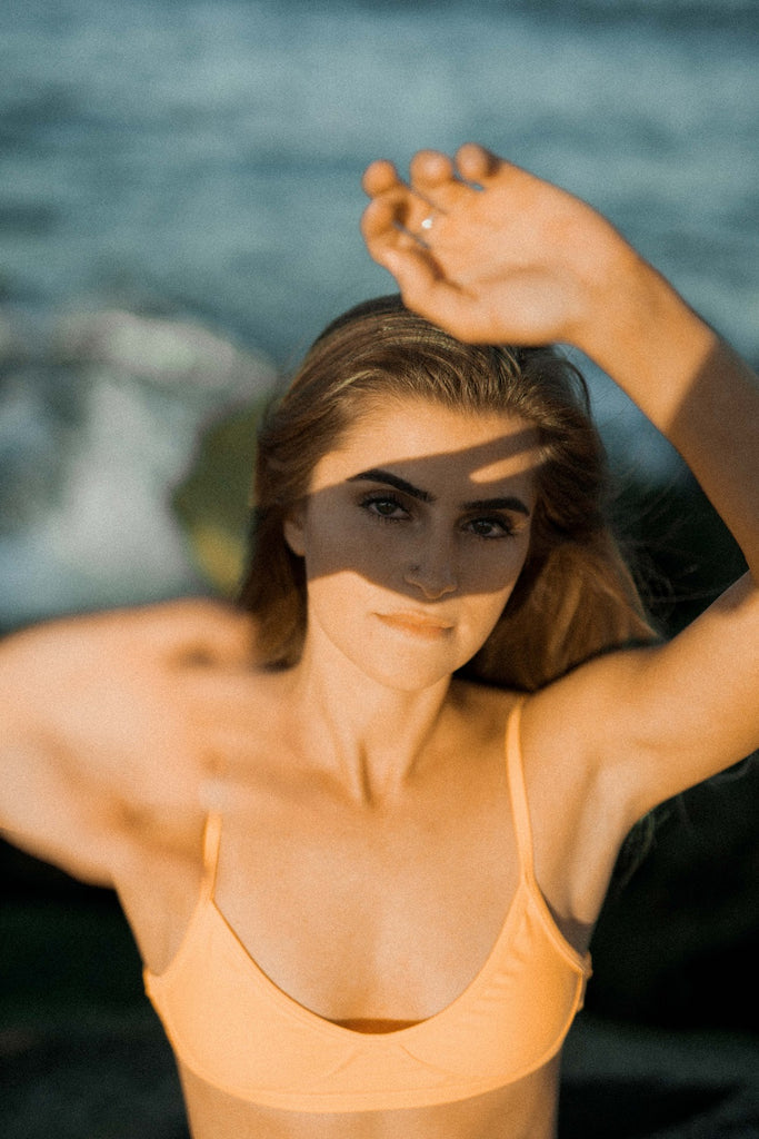 young woman in a swimsuit hiding her face from the sun