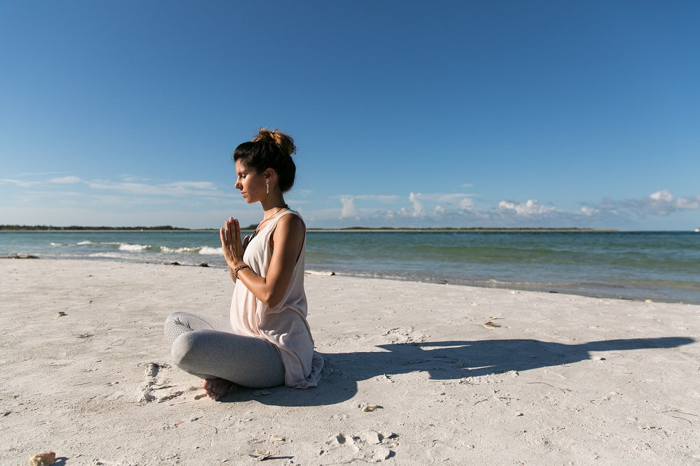 young woman meditating on the beach