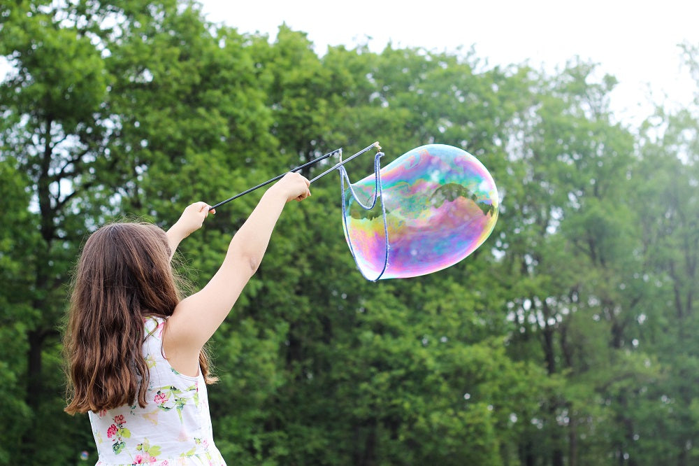 petite fille faisant une grosse bulle de savon