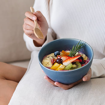 Eine Frau isst gesunde Lebensmittel in einer Bowl, um an den Beinen abzunehmen.
