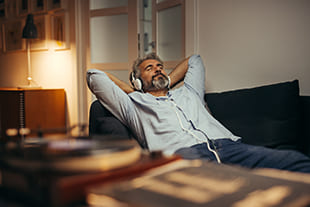 Mann entspannt mit Kopfhörern auf dem Sofa