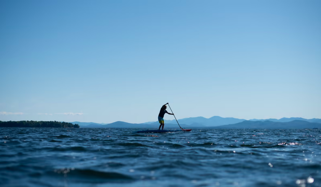Lake Champlain paddle boarding on blue water with blue mountains in background