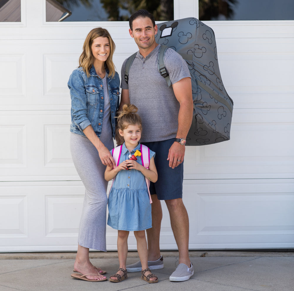 Family standing together with man carrying the Disney Baby Single & Double Stroller Travel Bag, Mickey Black